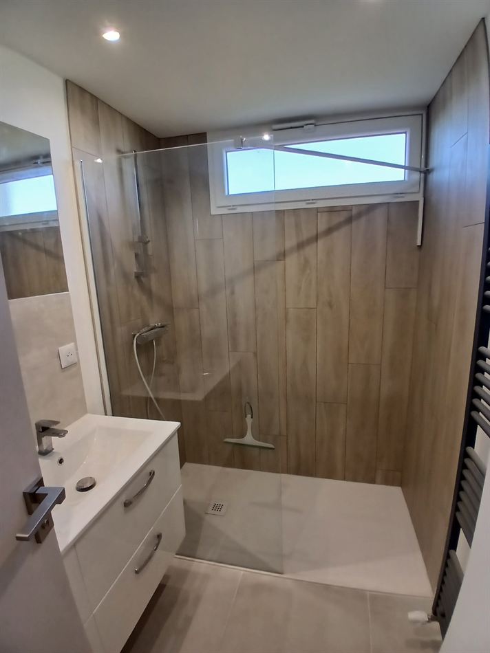 Salle de bains terminée avec douche à l'italienne et carrelage effet bois