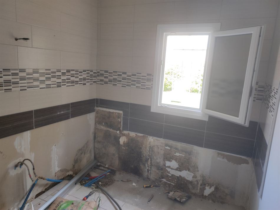 Salle de bains en travaux, ancienne baignoire déposée et murs à reprendre